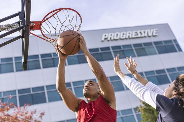 Man and woman playing basketball outside of Progressive building