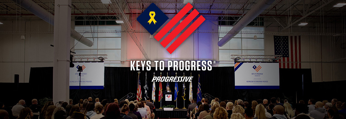 The Keys to Progress and Progressive logos above a person standing at a podium in front of a seated audience.
