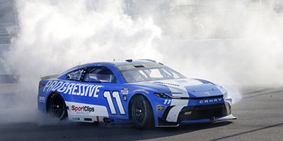 Denny Hamlin's number 11 Toyota Camry X S E for the 11 NASCAR Cup Series on a track doing doughnuts.
